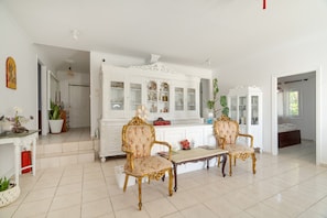 A spacious room with a white cabinet, two ornate chairs, a small table, and a potted plant. - Room 'Ground Floor' with Sea View, Shared Pool and Wi-Fi (Nikiana)