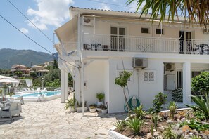 A white building with a balcony, a swimming pool, and potted plants. - Room '1st Floor' with Sea View, Shared Pool and Wi-Fi (Nikiana)