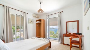 Ein Schlafzimmer mit einem Bett, einem Holztisch, einem Stuhl, einem Kleiderschrank und einem großen Fenster mit Blick.