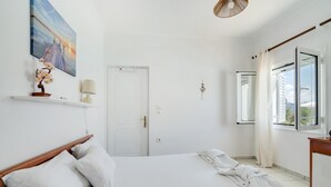 Una camera da letto con un letto, una porta, una finestra con tende, una lampada a parete e un quadro.