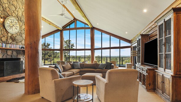 Una sala de estar amplia con un sofá modular grande, una chimenea, un televisor y una pared de piedra.