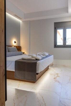 A modern bedroom with a bed, bedside table, and a window. - Marina A1 Apartment with Jacuzzi, Sea View, Wi-Fi and Air Conditioning (Kardamyli)