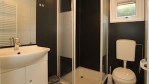 Ein Badezimmer mit Duschkabine, Toilette und Waschbecken mit Spiegel.