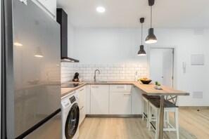 Eine moderne Küche mit Kühlschrank, Waschmaschine, Spüle und Holzarbeitsplatte.
