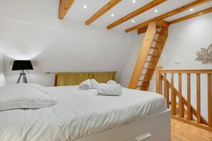 Un dormitorio con cama, lámpara, escalera de madera y un adorno en la pared.