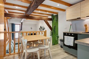 Una cocina moderna con vigas de madera, una mesa de comedor con sillas y un jardín vertical verde.