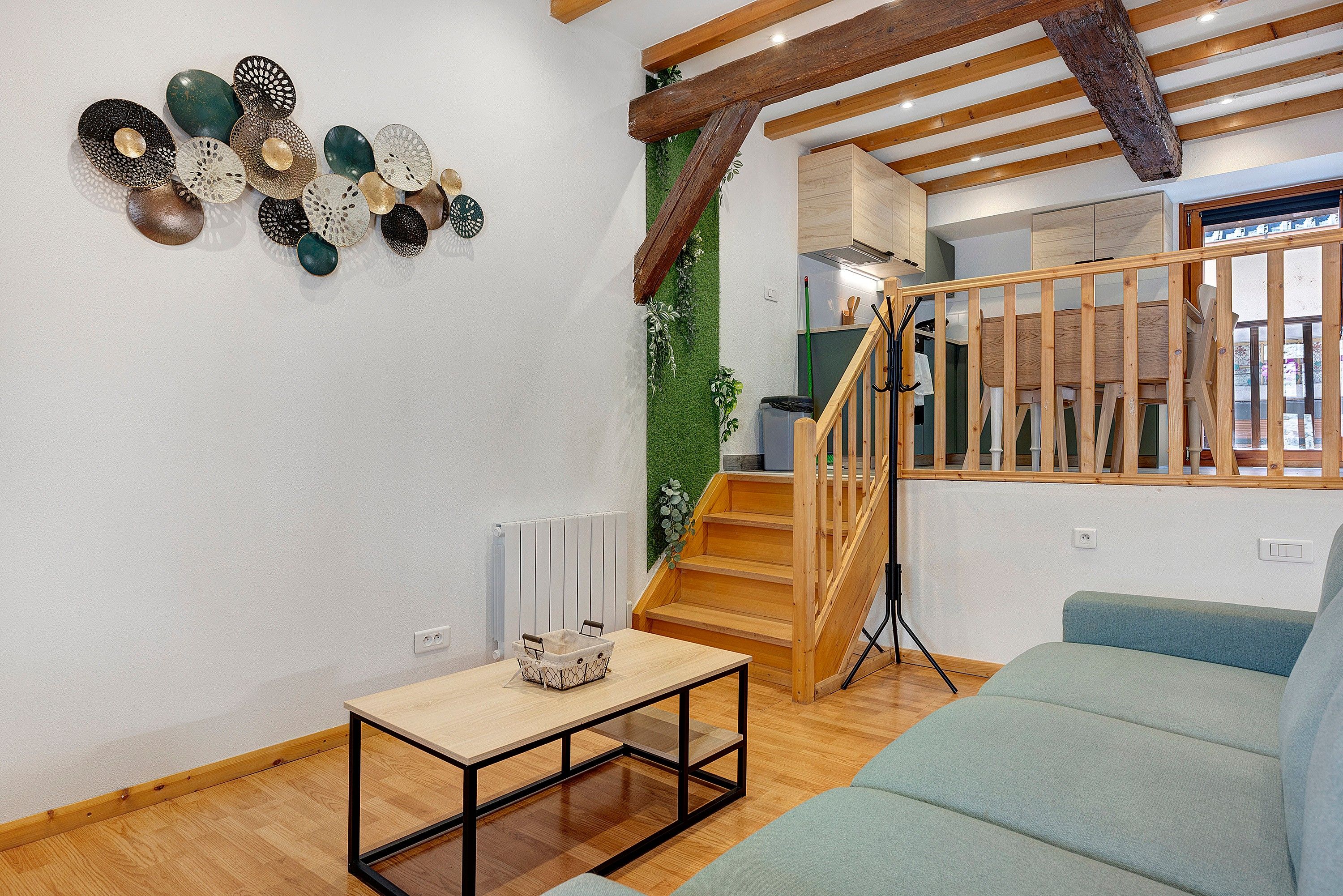Interior moderno com escada de madeira, parede verde e uma mesa com cesta.