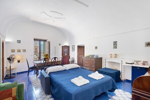 A bedroom with a bed, a desk, a chair, a fan, and a view of the outside. - La Casa Del Giudice Amalfi Coast Apartment with Sea View, Private Terrace and Wi-Fi (Atrani)
