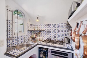 Une cuisine de taille réduite, équipée d’une cuisinière à gaz, d’un évier et d’une fenêtre.