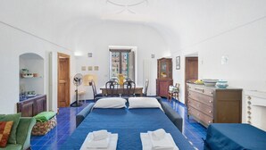Een kamer met een groot bed, een eettafel en een kitchenette.