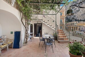 Une cour intérieure avec un escalier, des sièges extérieurs et une vue sur la ville.