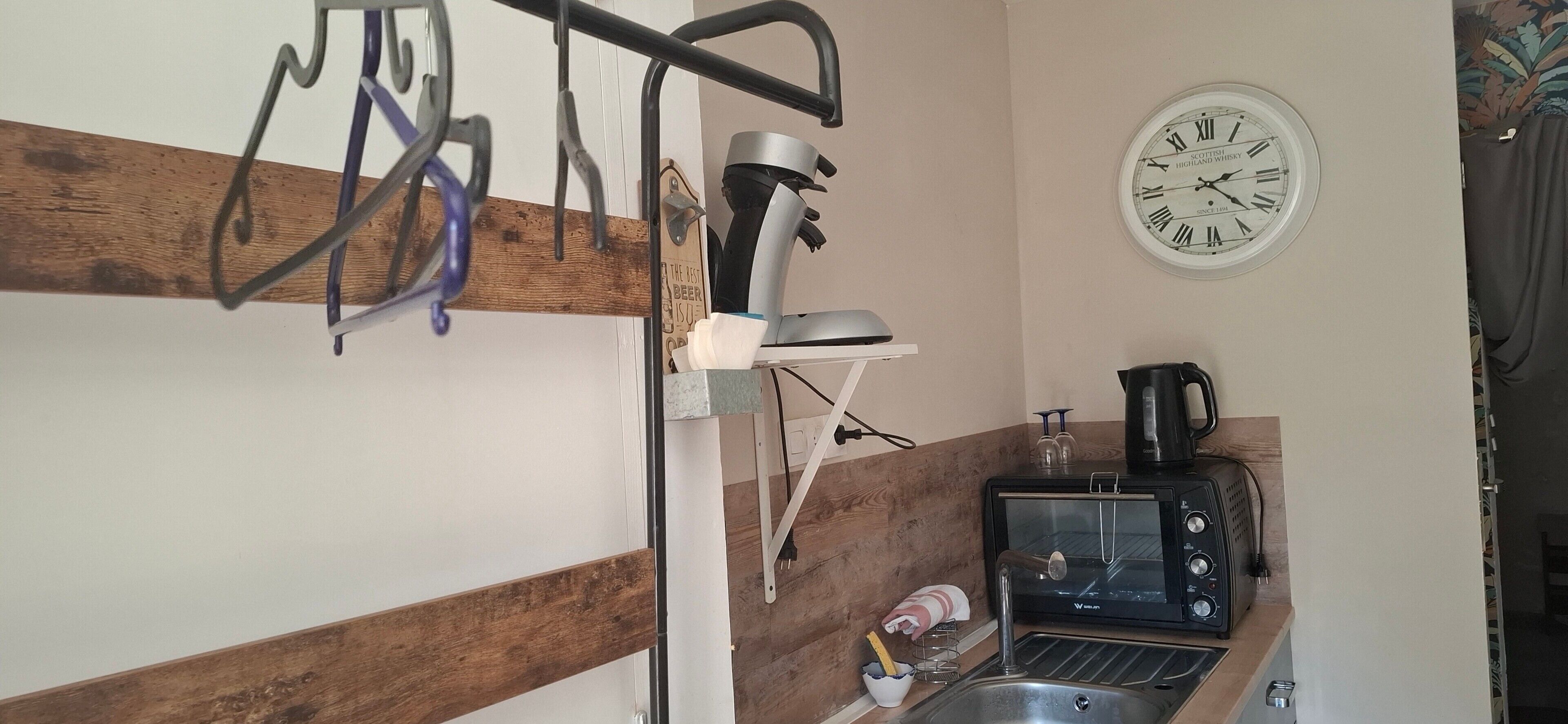 Ett kök med en kaffebryggare, en brödrost och en klocka på väggen.