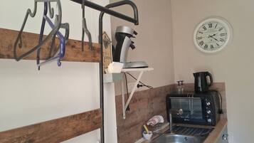 Ett kök med en kaffebryggare, en brödrost och en klocka på väggen.