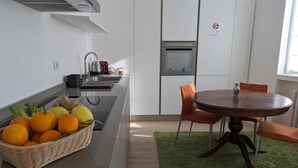 Une cuisine moderne équipée d’un four encastré, d’un évier et d’un coin repas avec une table ronde et des chaises.