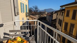Un balcon avec un panier en osier rempli de fruits, une balustrade blanche et des bâtiments en arrière-plan.