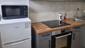 Eine Küchenzeile mit Mikrowelle, Backofen, Spüle und Holz Arbeitsplatte.