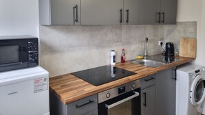 Eine Küchenzeile mit Mikrowelle, Spüle, Holz Arbeitsplatte, Schränken und einer Waschmaschine.