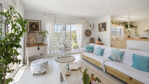 Un salón amplio con un sofá blanco, una mesa de centro de madera y un sillón colgante.