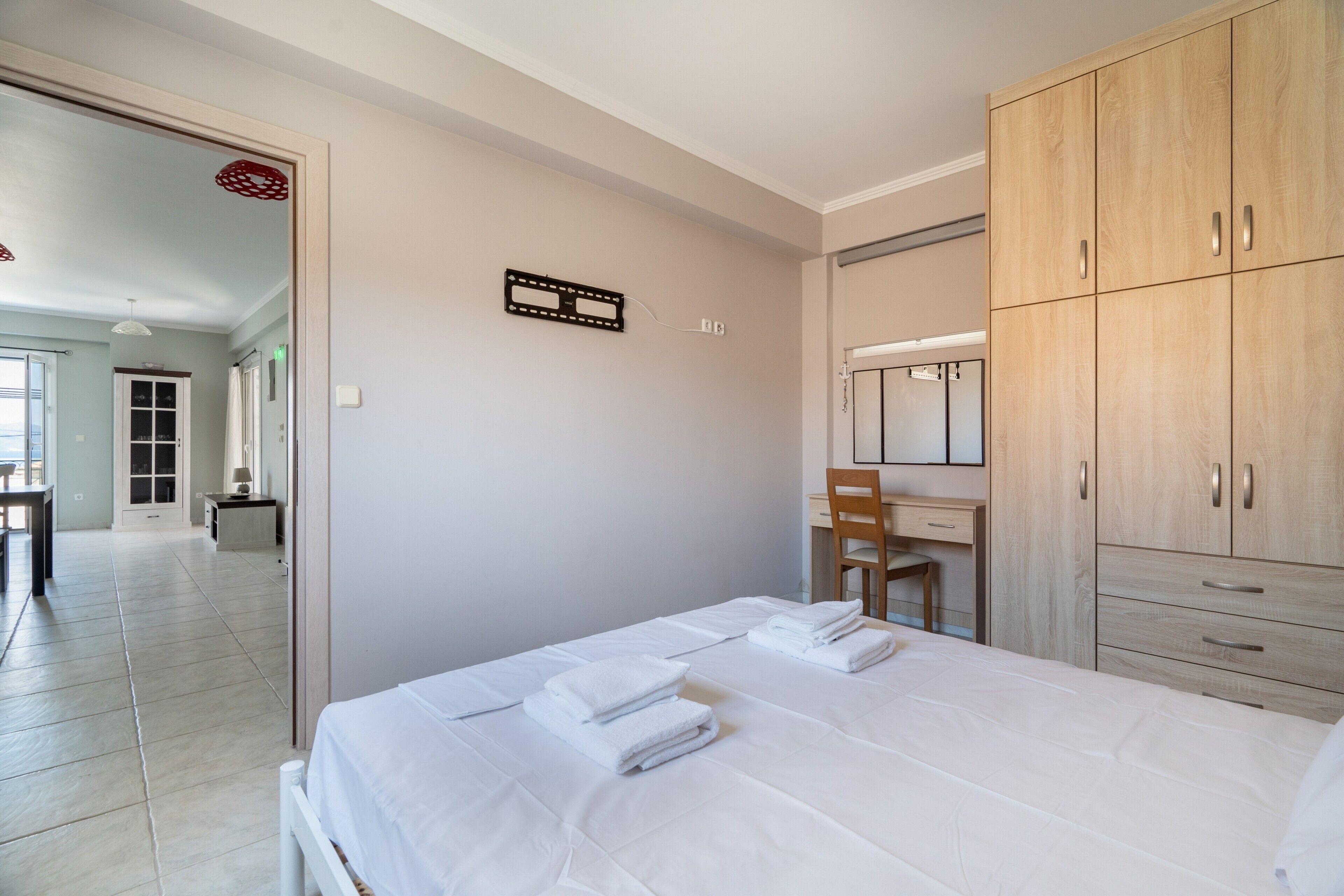 Un dormitorio con una cama, un armario de madera, un escritorio y una silla.