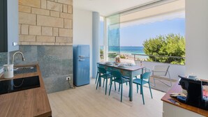Una cucina moderna con un frigorifero blu, un'area pranzo con sedie color acquamarina e un'ampia finestra vista mare.