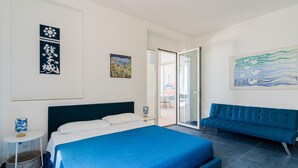Una camera da letto con un letto, un divano blu, un tavolino e opere d'arte alle pareti.