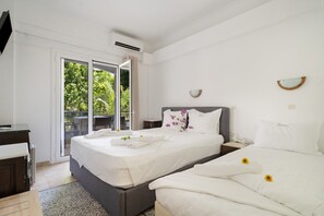 Ein Hotelzimmer mit Bett, Schreibtisch, Stuhl, Nachttisch und Blick auf Grün hinter dem Fenster.