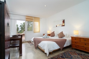 Ein Schlafzimmer mit Bett, Nachttischen, einem Sessel und Blick ins Freie.