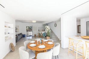 Un espace repas moderne avec une table ronde en bois, dressée pour six personnes, entourée de chaises blanches.