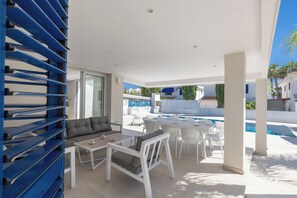 Moderni ulkotila, jossa on patio, uima-allas, valkoiset huonekalut ja sininen säilytysyksikkö.