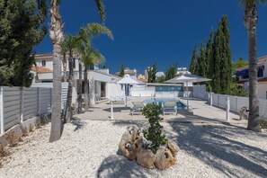 Ein Poolbereich mit Liegestühlen, einer kleinen Palme und einer dekorativen Felsformation.