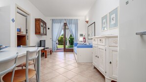 Uma cozinha com mesa, cadeiras, um armário e vista através de uma porta.