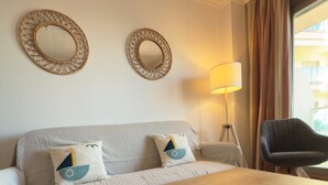 Une pièce comprenant un canapé, deux miroirs muraux, une lampe, une chaise et une table en bois.