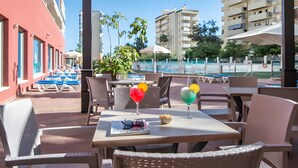 Un espace extérieur abrité, aménagé avec des tables, des chaises et des parasols.