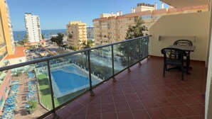 Un balcon donnant sur une piscine, avec une table à manger et une chaise.
