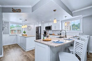 A modern kitchen with white cabinetry, a central island, and pendant lighting. - Relaxed Indian Rocks Beach Townhome Near Gulf (Indian Rocks Beach)