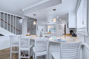 A modern kitchen with white cabinetry, a central island with bar stools, and pendant lighting. - Relaxed Indian Rocks Beach Townhome Near Gulf (Indian Rocks Beach)