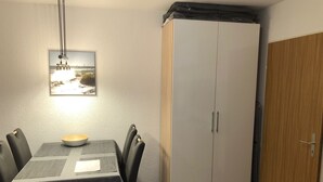 Uma sala de jantar com mesa, cadeiras, uma tigela, um quadro na parede e um guarda-roupa.