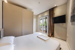 Un dormitorio con una cama grande, una puerta corrediza a un balcón y un televisor de pantalla plana montado en la pared.