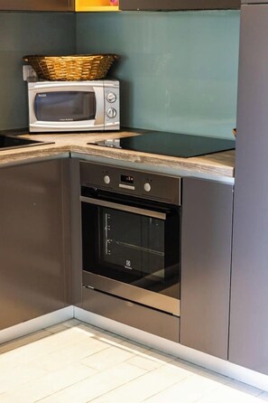 Eine Küche mit Einbauofen und Mikrowelle, einem Edelstahlkühlschrank und einer Holzausziehtheke.