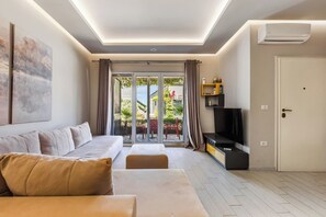 Ein modernes Wohnzimmer mit einer Couch, einem Fernseher und einer Schiebeglastür, die zu einem Außenbereich führt.