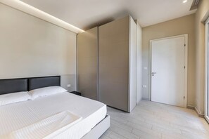 Ein modernes Schlafzimmer mit einem großen Bett, einem Kleiderschrank und einer Tür.