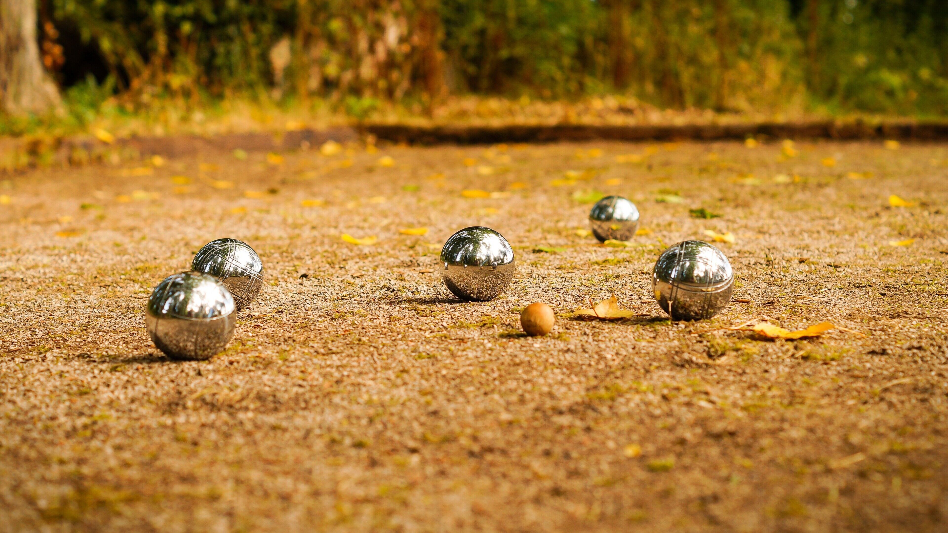 Een close-up van glanzende metalen ballen op een geribbelde ondergrond, mogelijk een speel- of activiteitenruimte.
