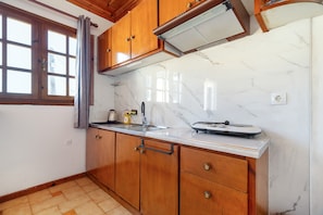 Una cocina con armarios de madera, encimera de mármol y ventana con cortinas.
