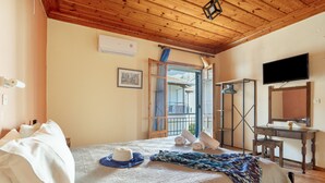 A bedroom with a wooden ceiling, a bed with white linens, a television, and a window with a view of mountains. - Mati Sea View Apartment with Sea View, Wi-Fi, and Air Conditioning (Nydri)