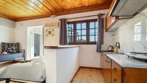 A compact kitchen with wooden cabinets, a marble countertop, and a window with curtains. - Mati Sea View Apartment with Sea View, Wi-Fi, and Air Conditioning (Nydri)
