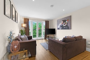 A modern living room with two sofas, a TV, and a glass coffee table. - Heathrow Living 2BDR 2BA Apt 11-360stays (Stanwell)