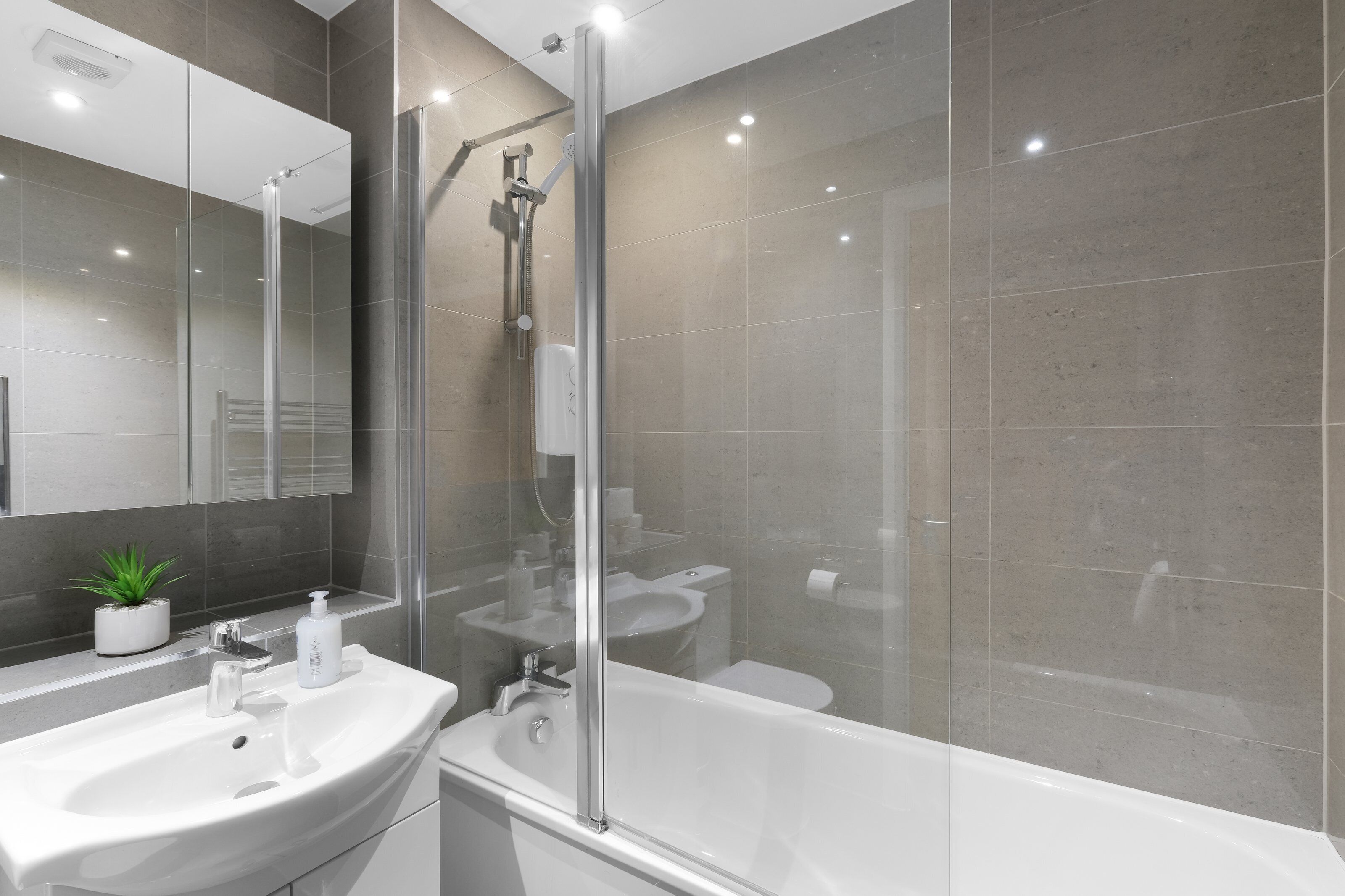 A modern bathroom with a glass-enclosed shower, a sink, and a bathtub.