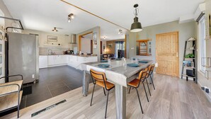 A modern kitchen with a central island, stainless steel appliances, and a dining area with a large table and chairs.