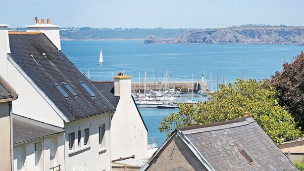 A coastal view with buildings, a marina, and a sailboat.