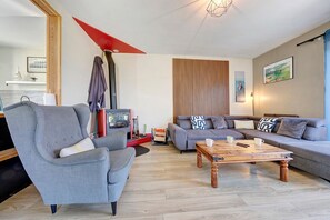 Ein modernes Wohnzimmer mit einem grauen Sofa, einem Holztisch und einer roten Lampe.